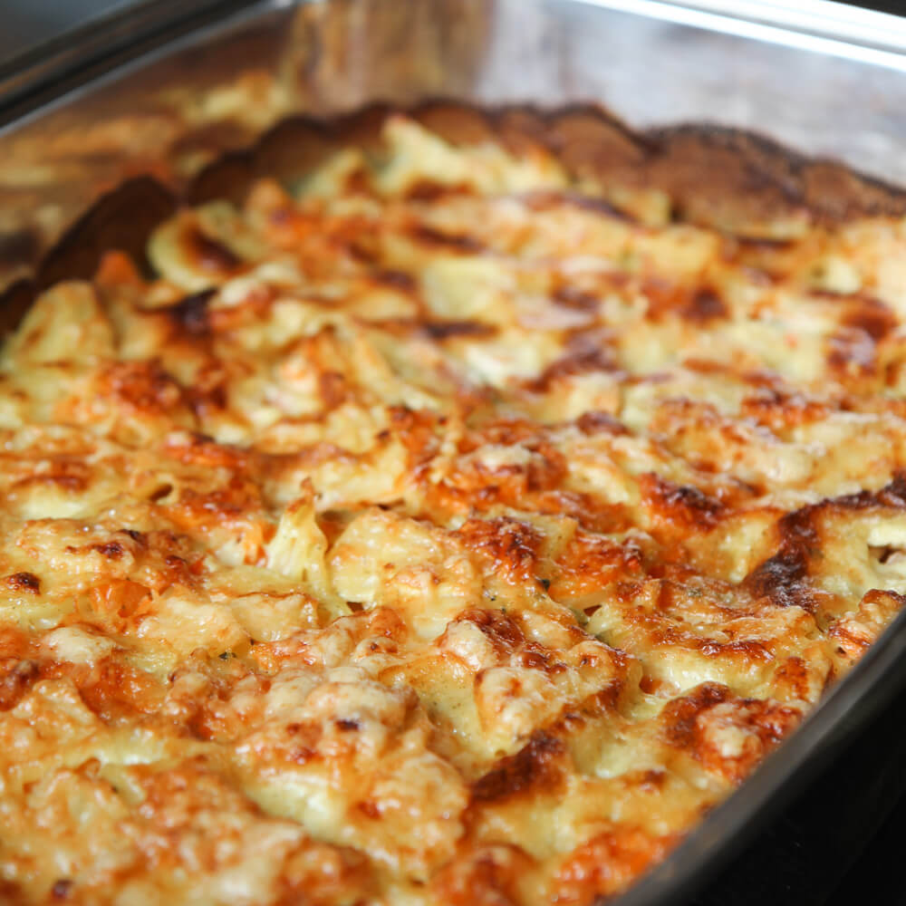 Rezept für Kartoffel-Karottenauflauf mit Käse überbackener Kartoffel-Karottenauflauf in einer schwarzen Auflaufform