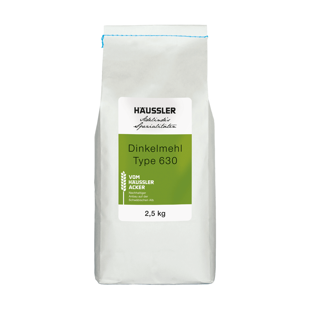 Dinkelmehl Type 630 vom Häussler Acker Weiße Mehltüte mit blauem Faden an der Kopf-Seite der Mehltüte um die Tüte aufzureißen. Auf der weißen Mehltüte ist ein grün-weißes Etikett aufgeklebt.