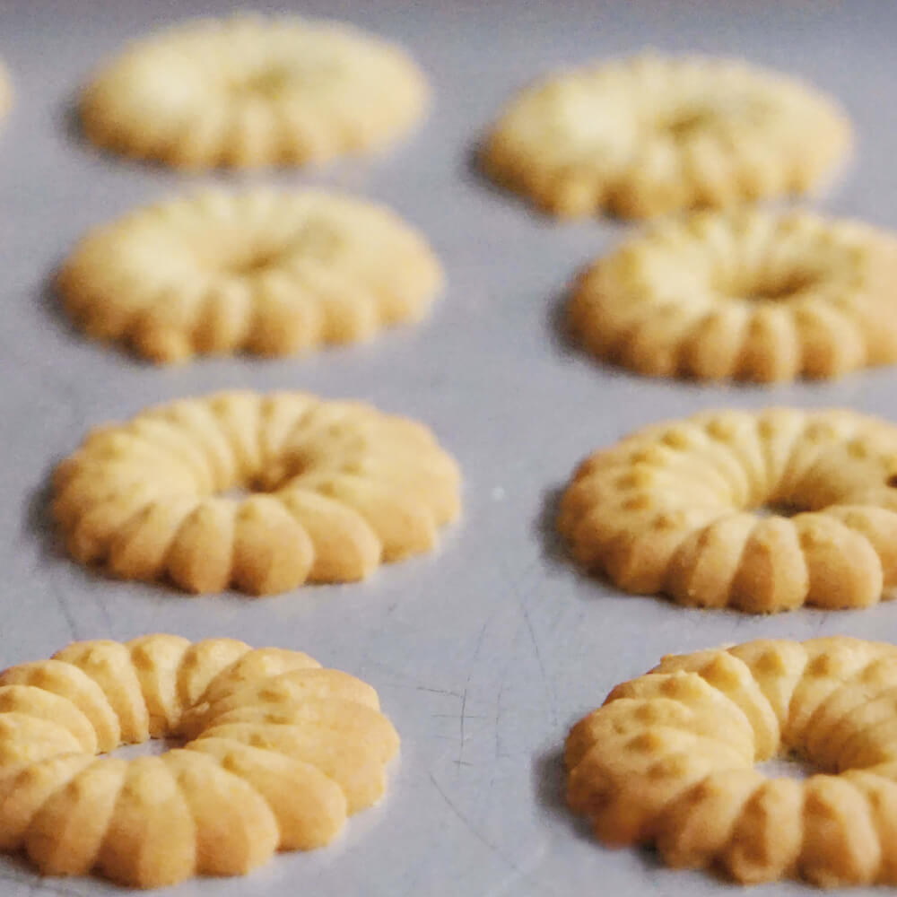 Runde Plätzchen in Blumenform. Diese liegen auf einem grauen Untergrund.