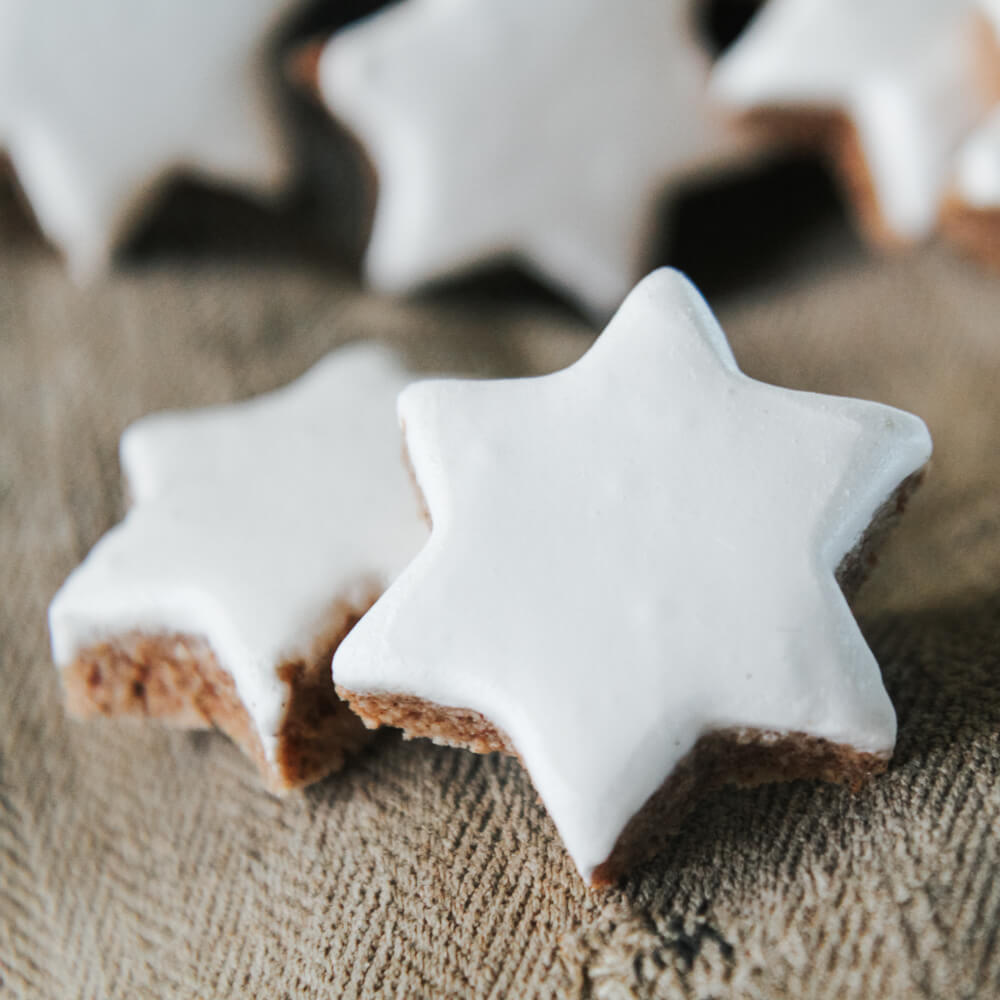 Rezept für Zimtsterne Zimtsterne mit einer Eiweißglasur auf einem grauen Tuch