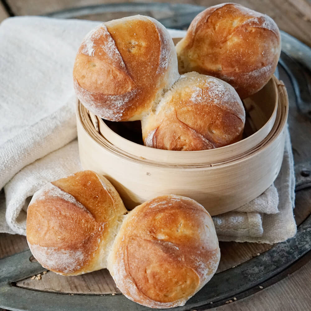 3 runde Doppel-Brötchen mit Lievito Madre in einer runden Holzform serviert