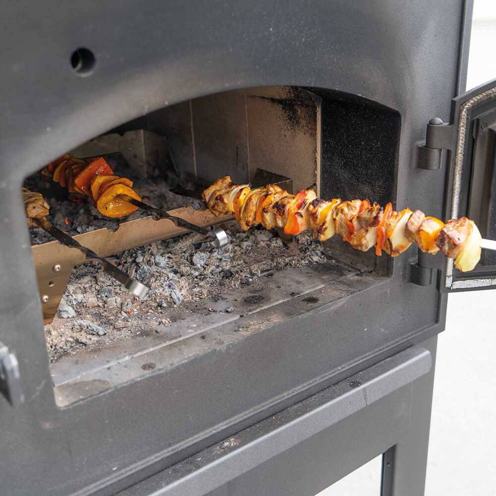 Grillrost und Grillspieße im Holzbackofen mit Fleisch und Gemüse