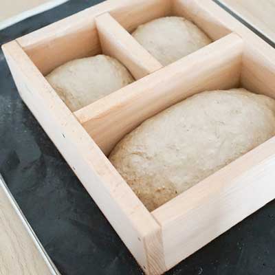 Holzbackrahmen aus Buchenholz Bolzbackrahmen gefüllt mit drei unausgebackenen Broten
