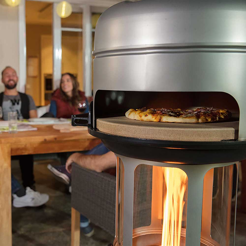 Pizzastein für Pelletgrill Pizzastein mit einer frisch gebackenen Pizza im Pelletgrill mit Grillaufsatz und Deckel in einer Gartenhütte.