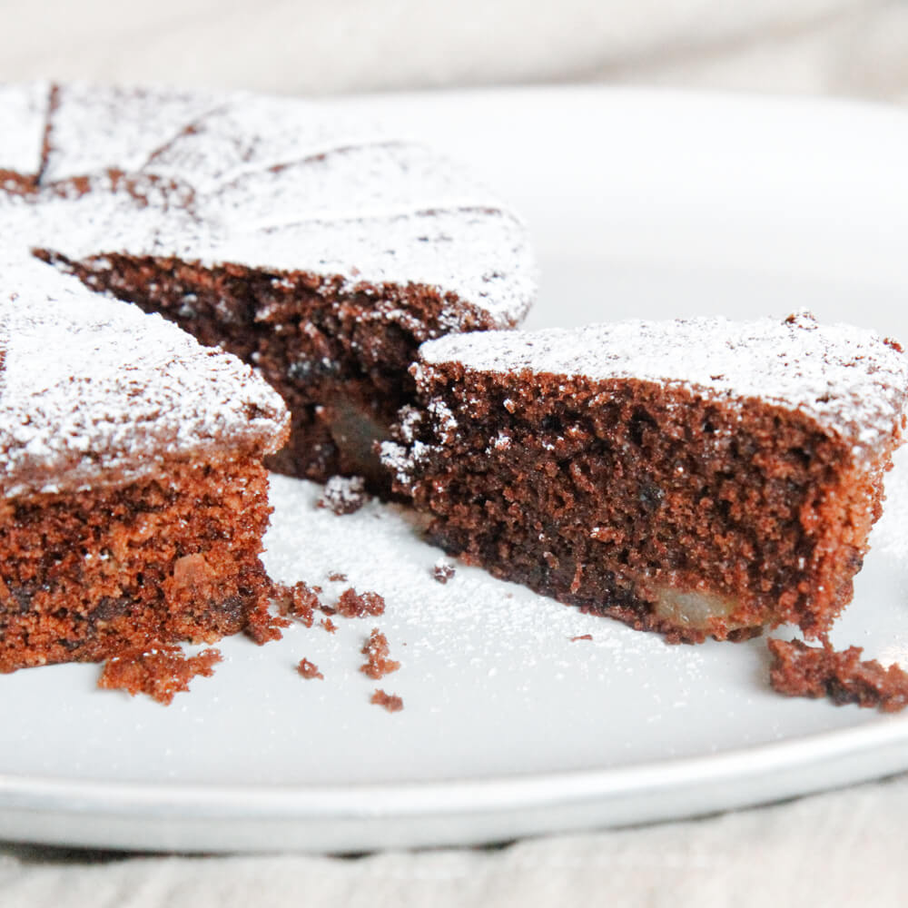 Rezept für Schoko-Birnenkuchen glutenfrei Schokokuchen mit Birnen und Puderzucker bestreut auf einem weißen Teller