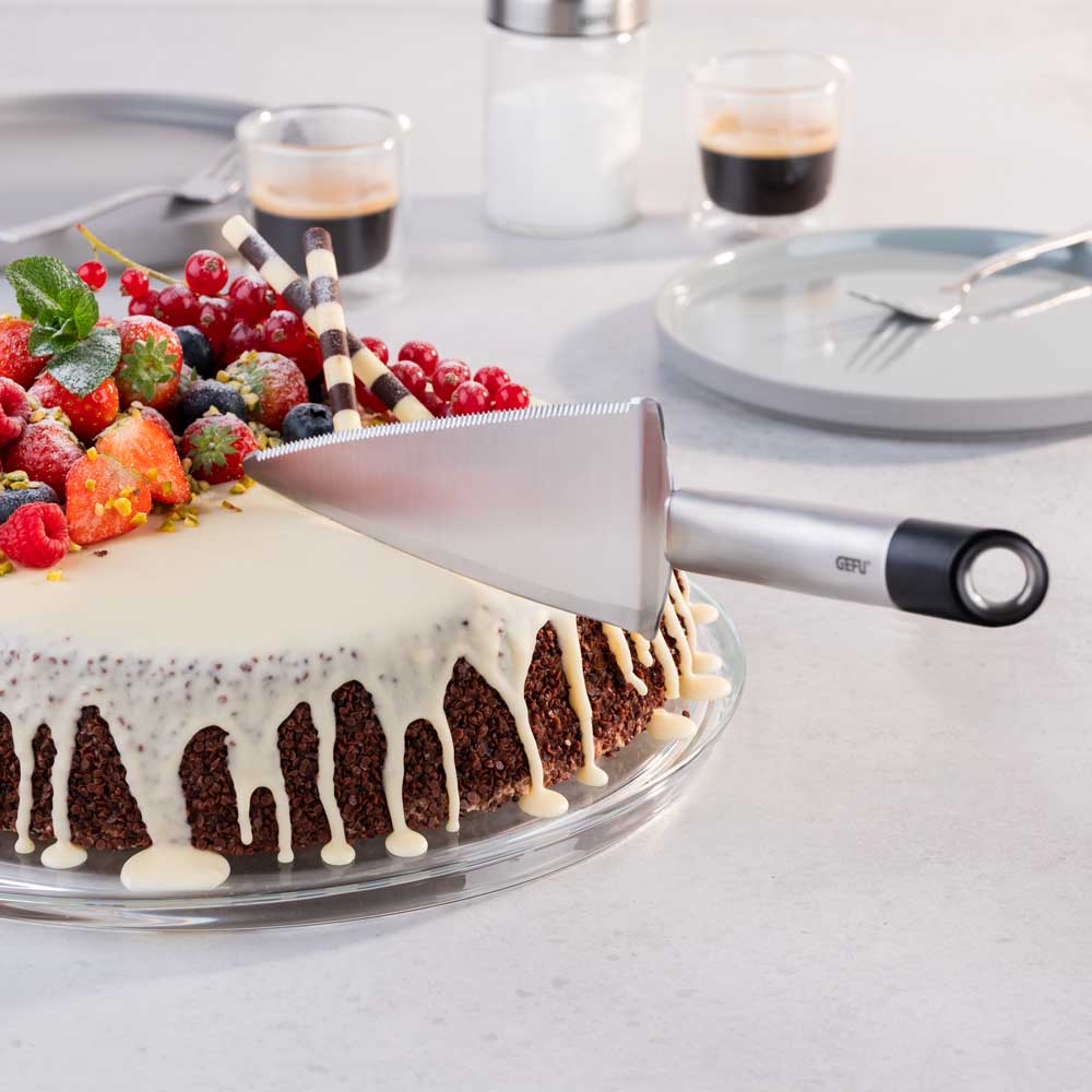 Torte und Gedeck auf einem weißen Tisch. Der Tortenheber wird angewandt