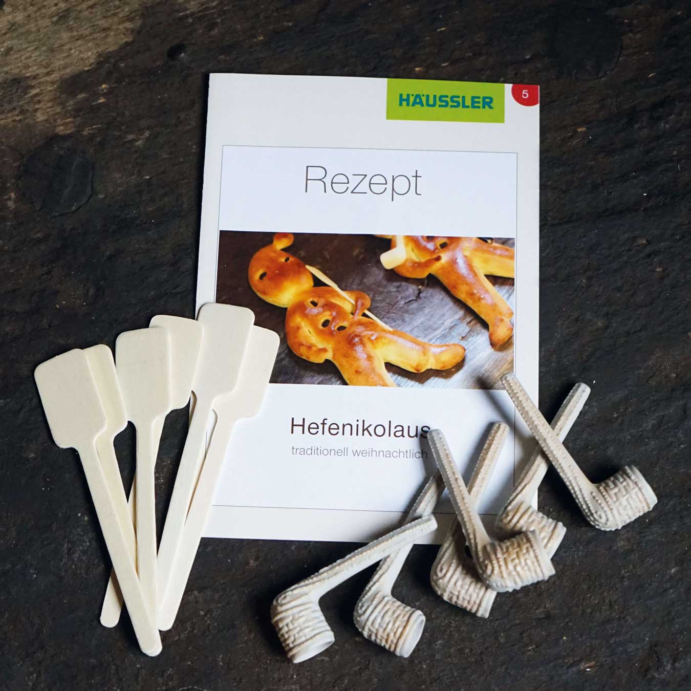 Deko-Backschieber und Tonpfeifen mit einem Rezept für Hefenikoläuse abgebildet.