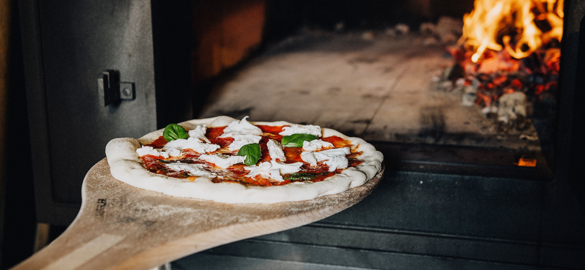 Pizza kommt in Holzbackofen Pizza in Holzbackofen