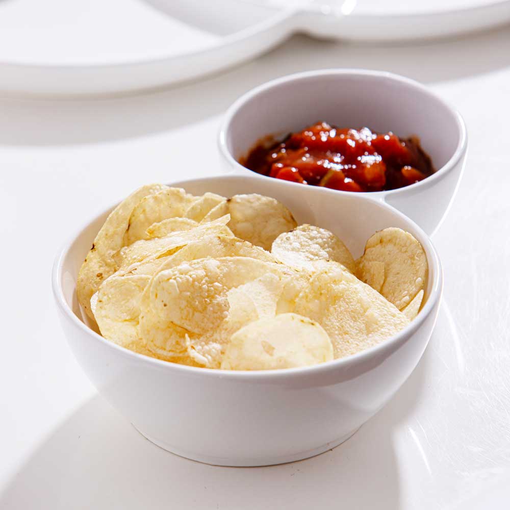 Servierschale 2-teilig, zwei verbundene weiße Porzellanschüsseln, in der größeren sind Kartoffelchips und in der kleiner ein roter Dip, Farbe weiß