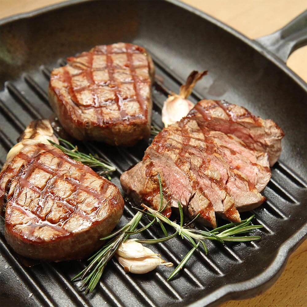 Eisengusspfanne in der fleisch mit Knoblauch und Rosmarin gebraten wird