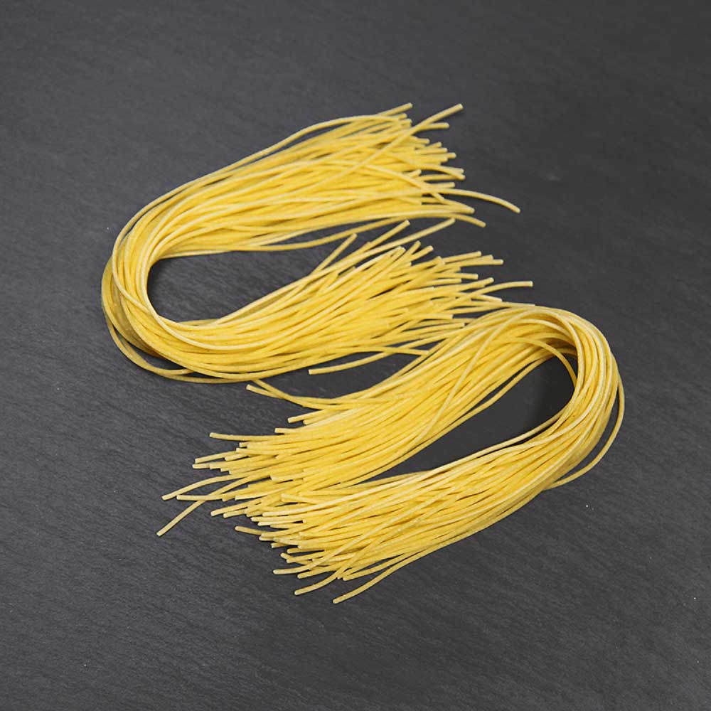 Auf dem Bild befinden sich Spaghetti die auf einer grauen arbeitsplatte liegen.