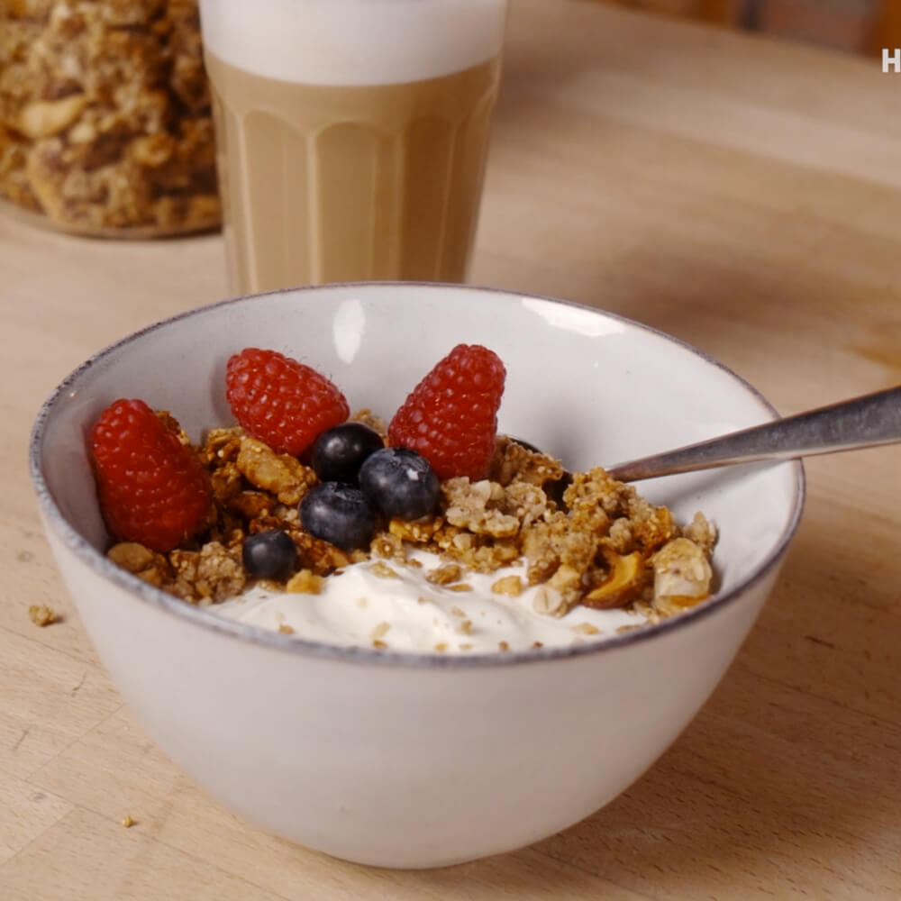 Müslischale mit Joghurt, Beeren und selbstgemachtem Knuspermüsli in weißer Müslischale