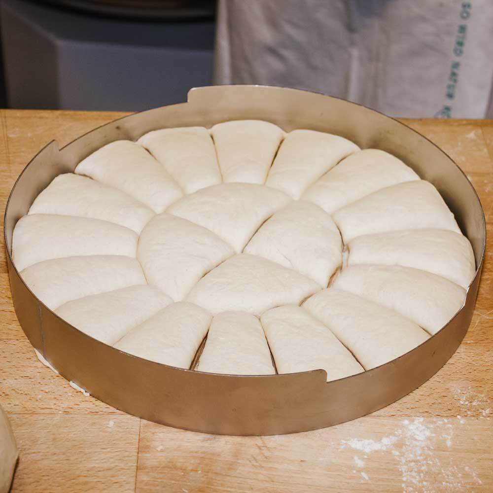 Teigteiler rund Abgestochene Teiglinge in der runden Form auf einer Küchenarbeitsplatte.