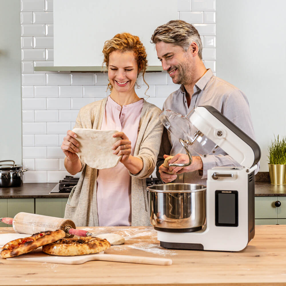 Zwei Personen ziehen den Pizzateig aus 