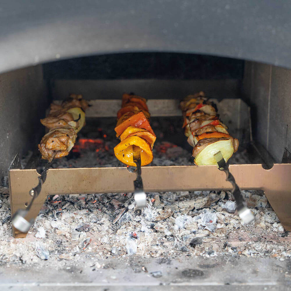 Grillrost mit Grillspieße Grillrost und Grillspieße im Holzbackofen mit Fleisch und Gemüse