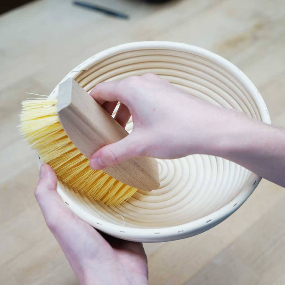 Gärkörbbürste Gärkörbbürste in der Anwendung beim auskehren eines Gärkorbs auf einer Abeitsplatte.