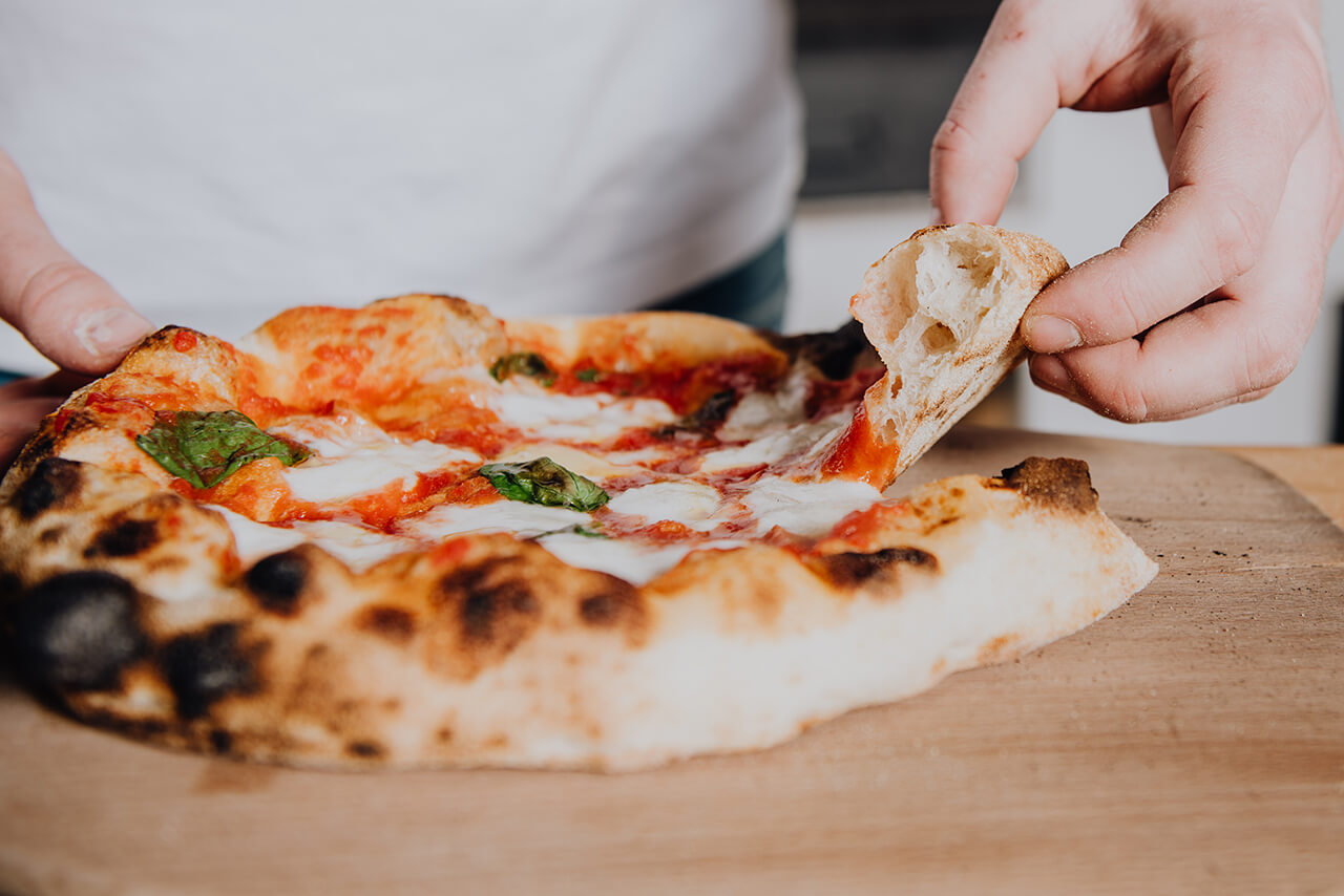 Fertige Pizza wird aufgeschnitten