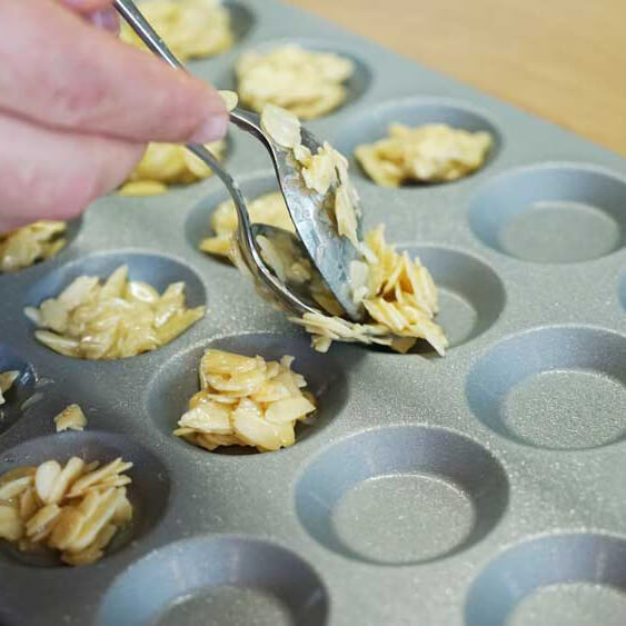 Es wird gerade eine Mandel-Karamell Mischung in die Förmchen eingefüllt.