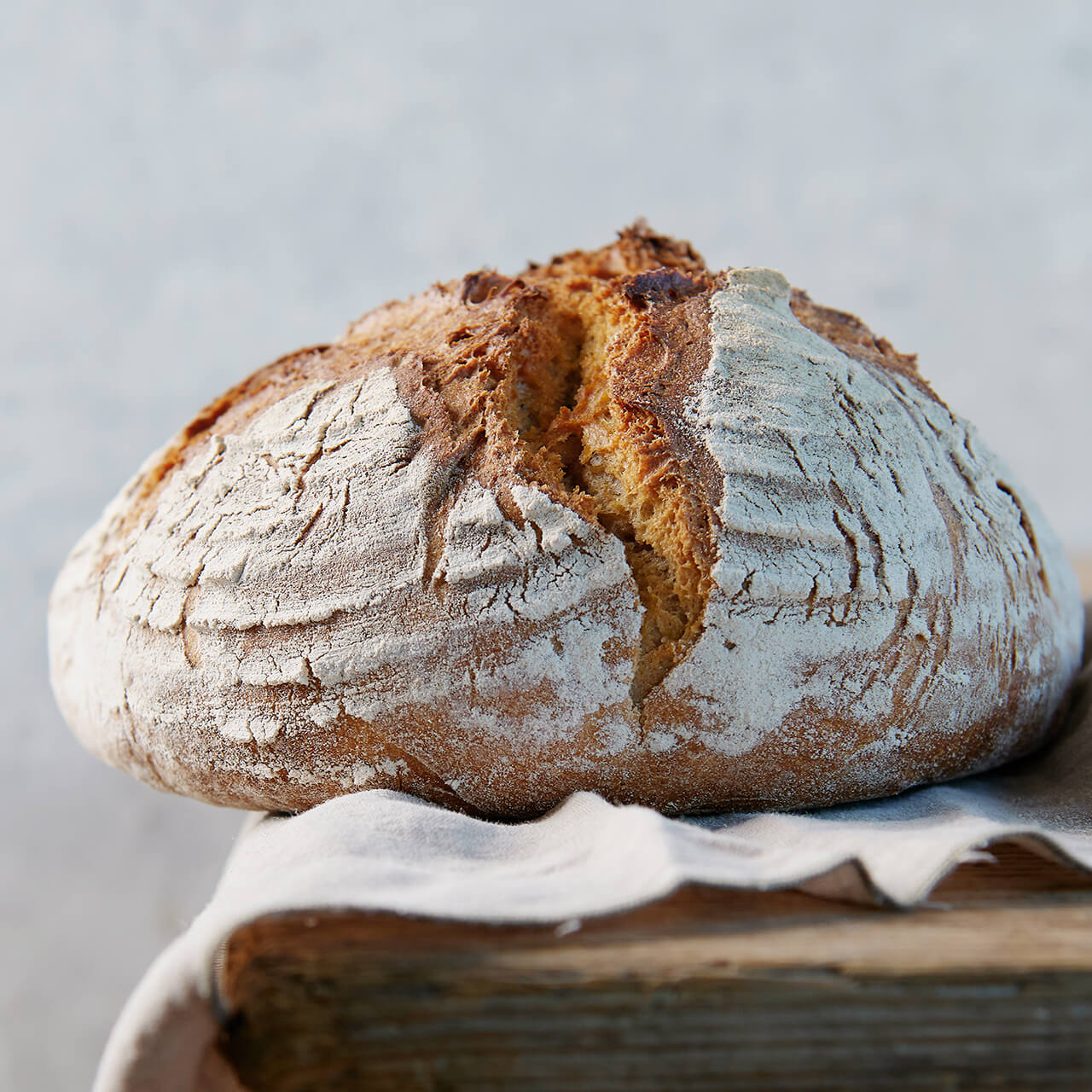 Großer Schwabenlaib mit bemehlter Kruste, liegend auf einem Leinentuch auf einem Holztisch