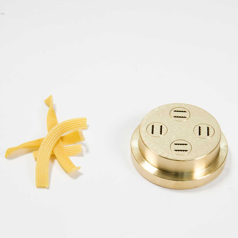 Matrize Nr. 58 - Zackenbandnudel Nudelmatrize Nr. 58 für Zackenband-Nudeln neben einigen Zackenband-Nudeln vor einem weißen Hintergrund.