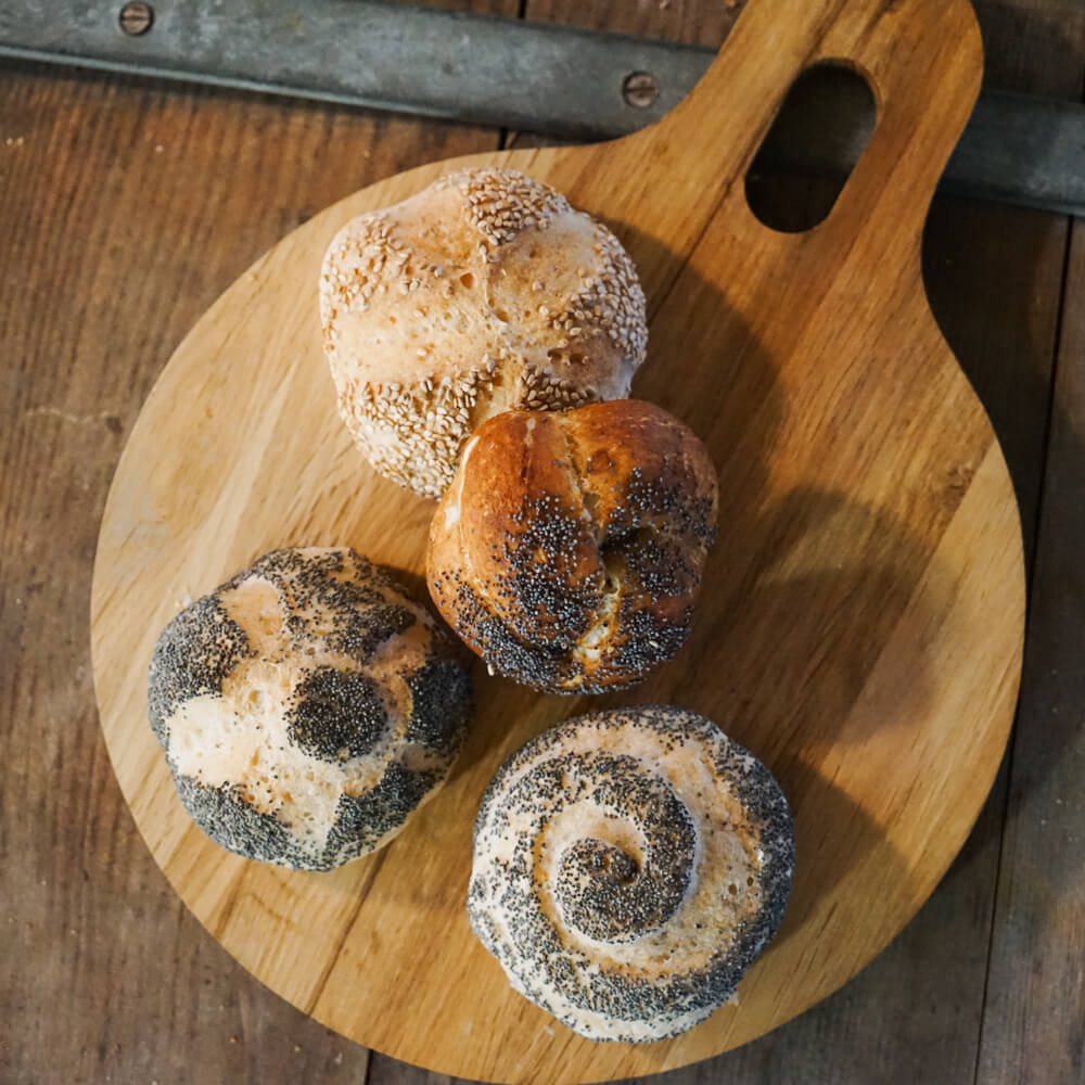 Mohn- und Sesambrötchen mit verschiedenen Mustern auf einem Holzbrett