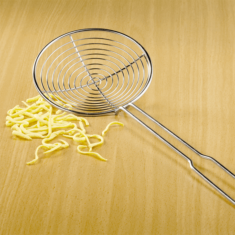 Silberner Schaumlöffel für Spätzle und Co. Der Schaumlöffel liegt auf einer Holz-Fläche und links davon liegen ein paar Spätzle