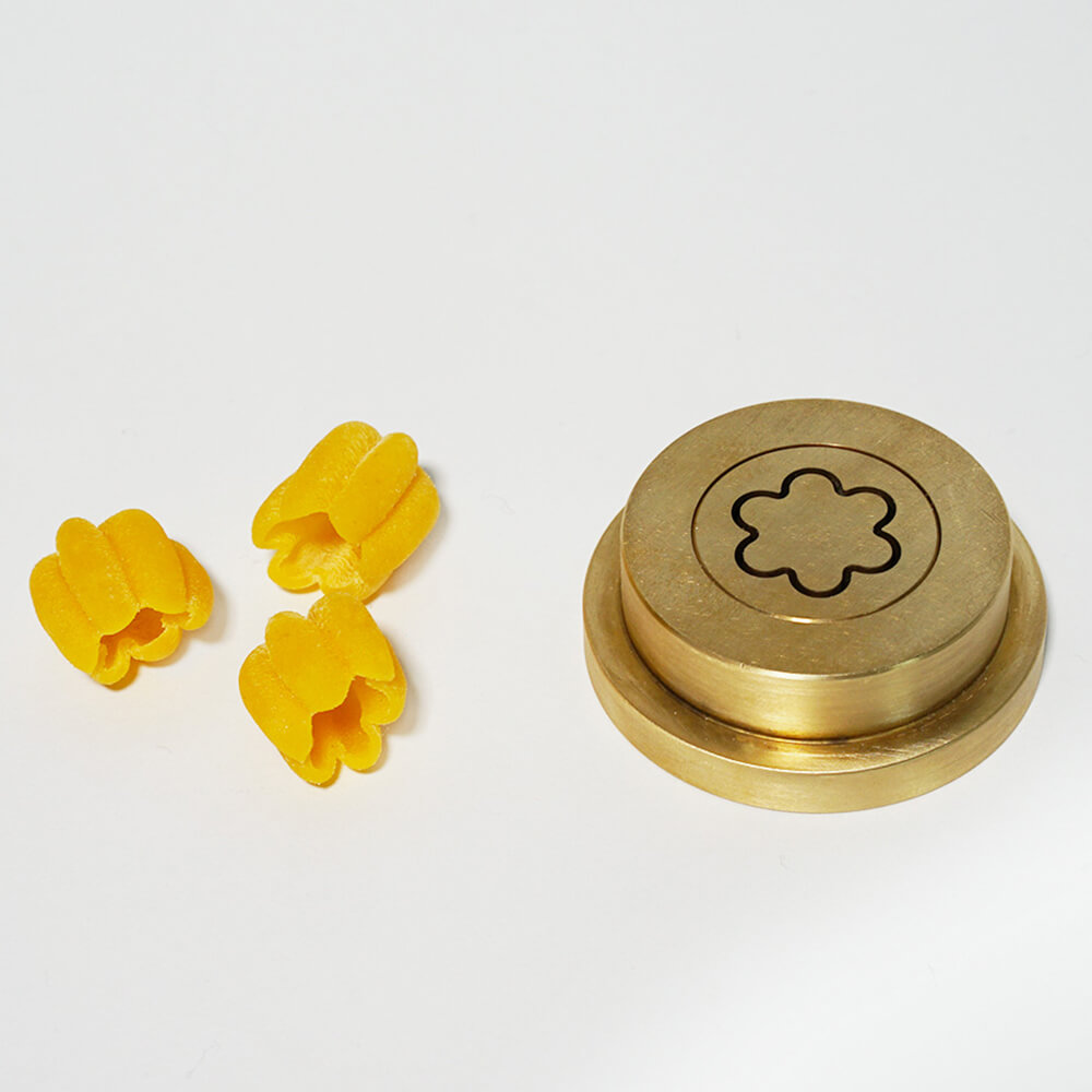 Nudelmatrize Nr. 374 für Blumen-Nudeln neben einigen Blumen-Nudeln vor einem weißen Hintergrund.