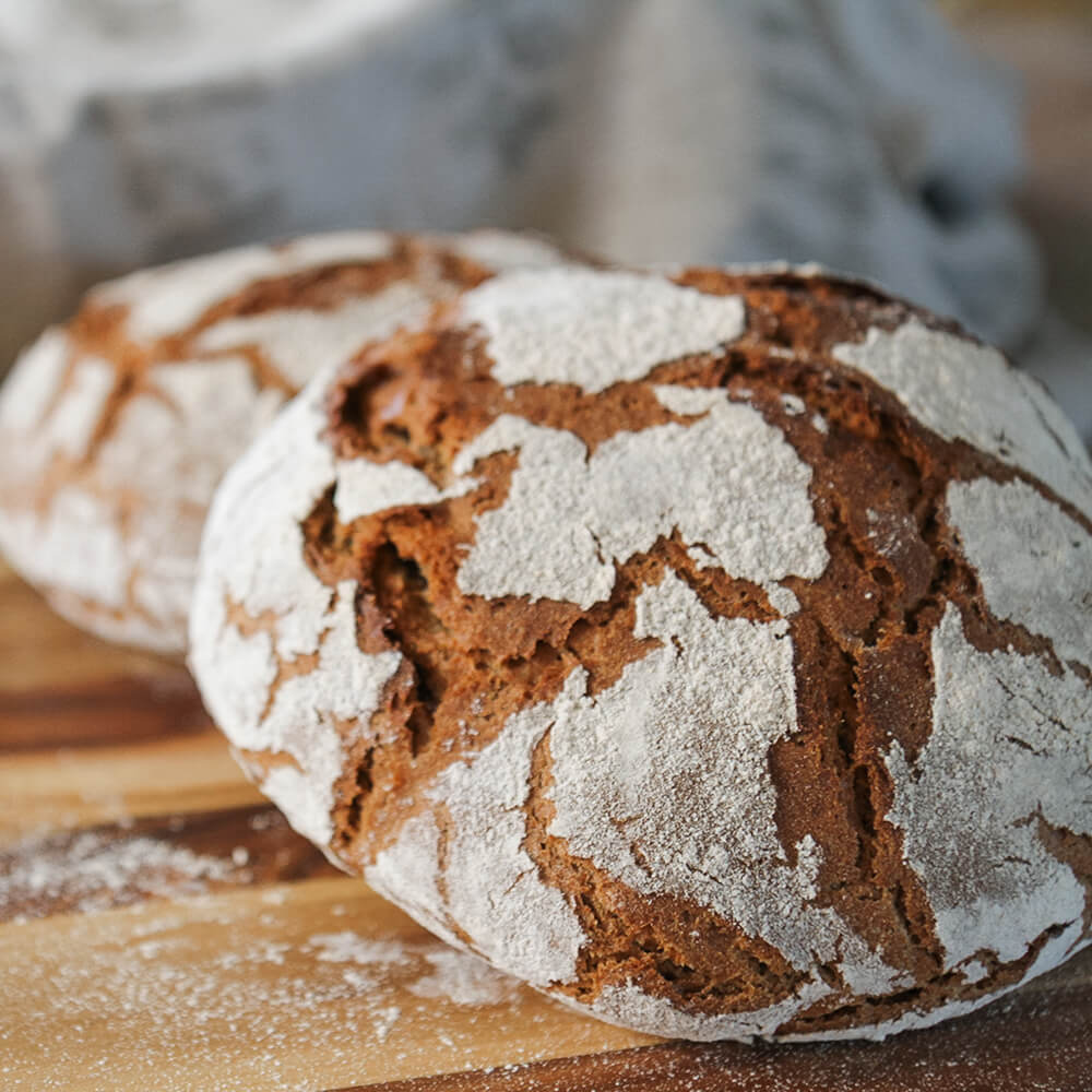 Rezept für Adelindes Roggen-Dinkelbrot 2 Roggen-DInkelbrote auf einem Holzbrett
