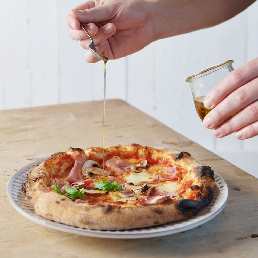 Luftige, krosse Pizza einfach mit dem Pizzamehl zuhause backen Luftige, Krosse Pizza mit Basilikum und Öl serviert