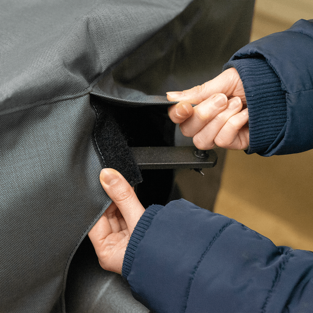 Hände, die eine Holzbackofenabdeckung mittels Klettverschluss verschließen