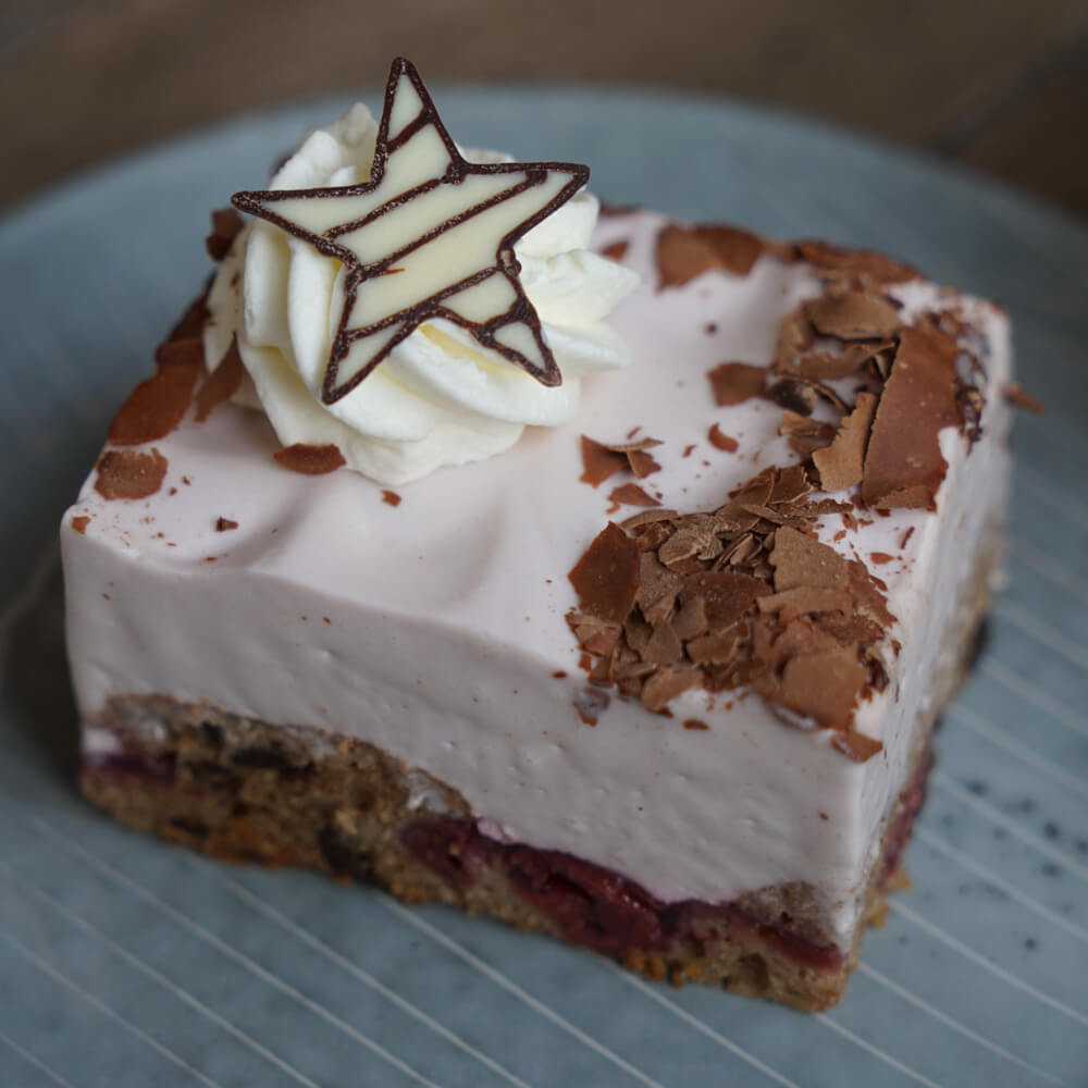 Rezept für Glühweinschnitten selbstgemachte Glühweinschnitten, mit einem dunklen Biskuitboden und einer Füllung aus Kirschen. Darauf kommt ein Sahnefond aus Sahne und Glühwein und wird mit etwas Sahne und einem weißen Schokoladenstern verziert