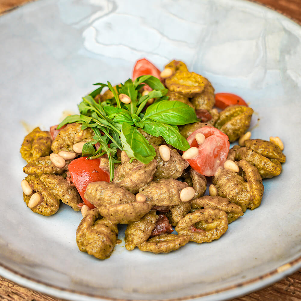 Rezept frische Gnocchi mit italienischen Gewürzen im Salat Braune Kräuter-Gnocchi mit einer gelben Vinaigrette als Salat angerichtet mit frischen und eingelegten Tomaten, Rucola und Pinienkernen