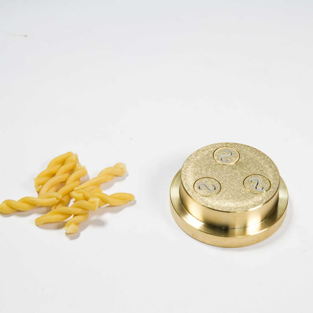 Nudelmatrize Nr. 51 für Zöpfle-Nudeln neben einigen Zöpfle-Nudeln vor einem weißen Hintergrund.