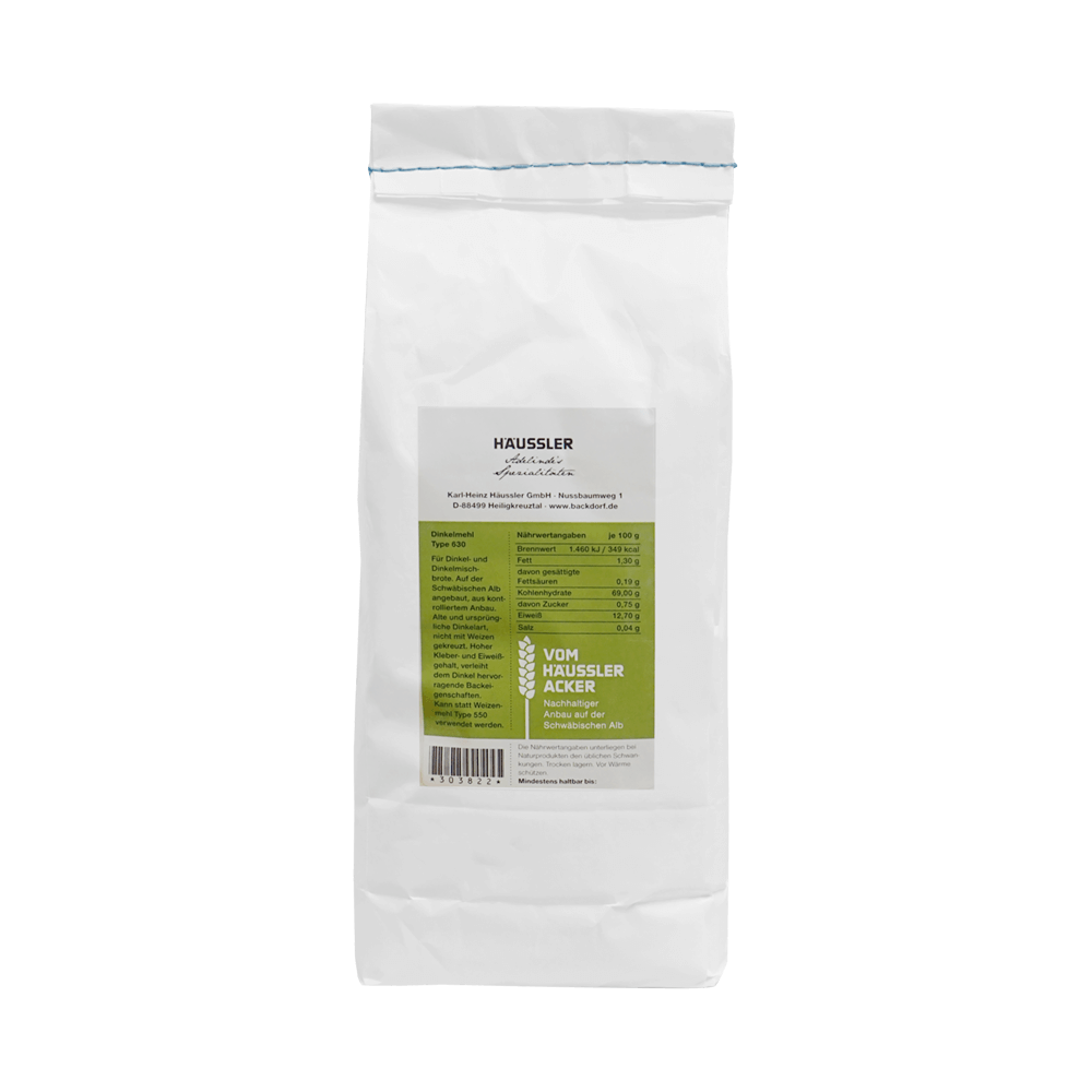 Weiße Mehltüte mit blauem Faden an der Kopf-Seite der Mehltüte um die Tüte aufzureißen. Auf der weißen Mehltüte ist ein grün-weißes Etikett aufgeklebt.