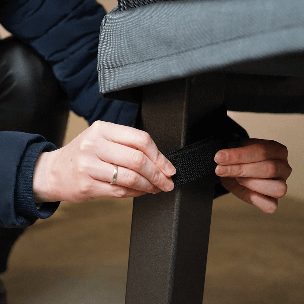 Hände, die eine Holzbackofenabdeckung mittels Klettverschluss an einem Standbein befestigen