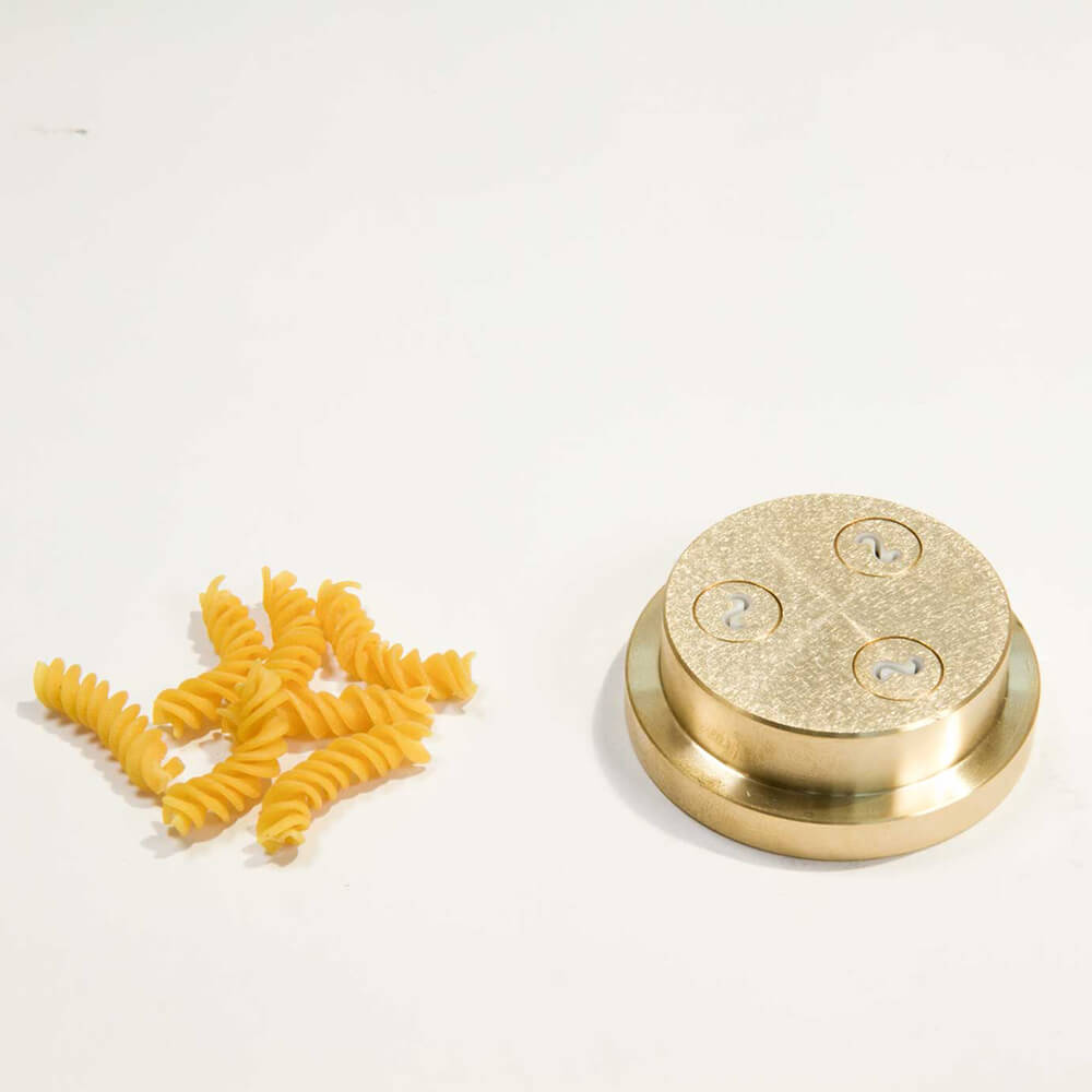 Matrize Nr. 49c - Fusilli/Spirelli Nudelmatrize Nr. 49c für Fusilli neben einigen Fusilli-Nudeln vor einem weißen Hintergrund.