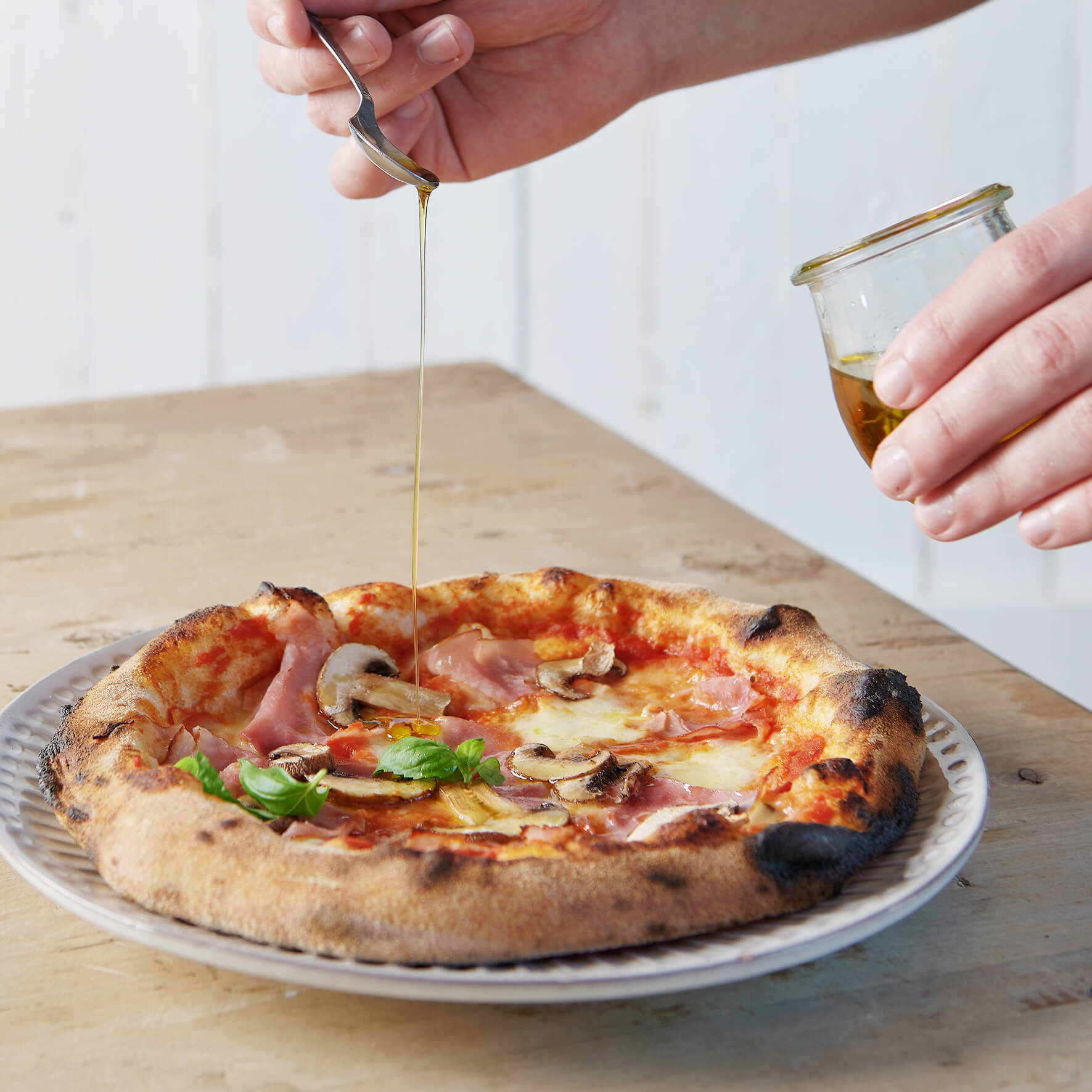 Luftige Pizza mit Tomatensoße, Pilze, Schinken auf einem Teller