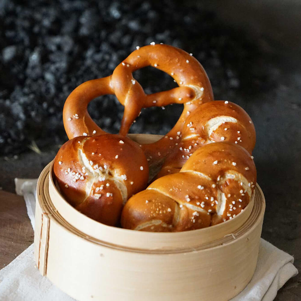 Frisch gebackenes Laugengebäck in einem Körbchen vor einem dunklen Hintergrund.