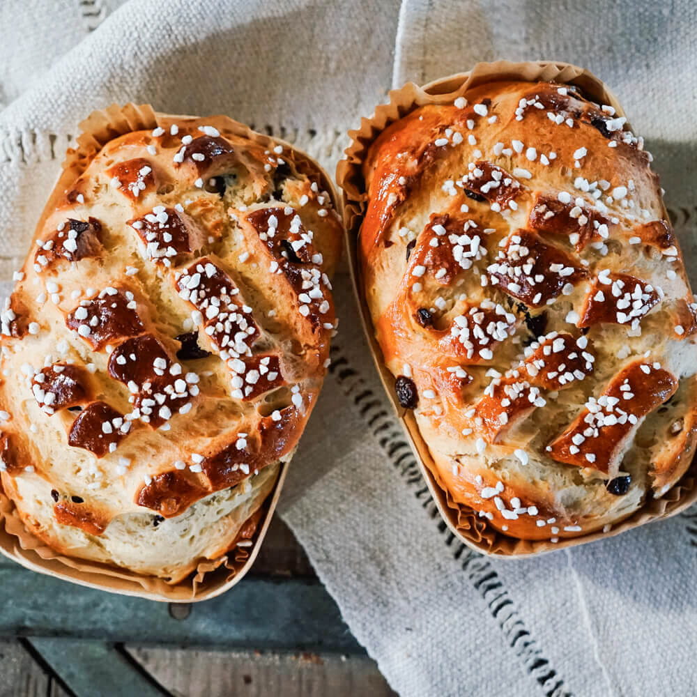 Rezept für Osterbrot in einer Holzbackform gebackenes Osterbrot mit Hagelzucker und Rosinen mit hellem Hintergrund