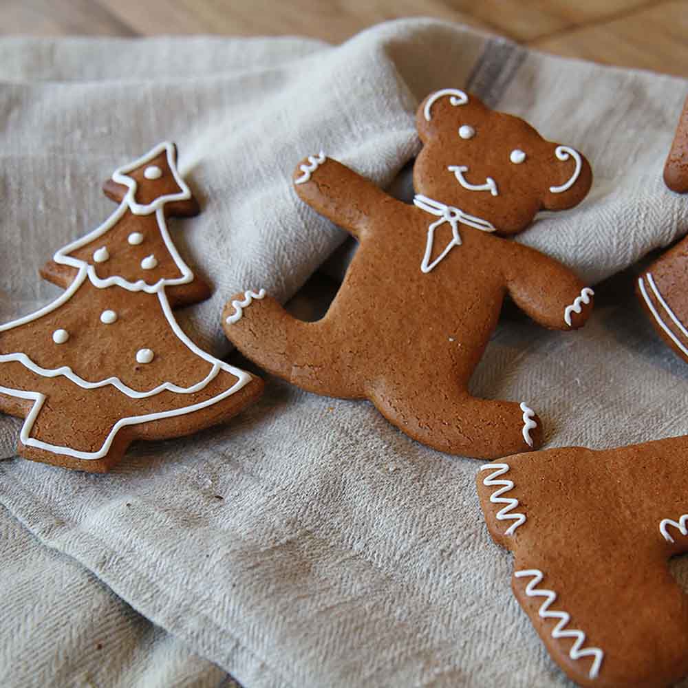 gebackene Lebkuchen mit Zuckergussverzierung in Form von einem Bären, einem Tannenbaum und einem Stiefel auf einem Leinentuch platziert.